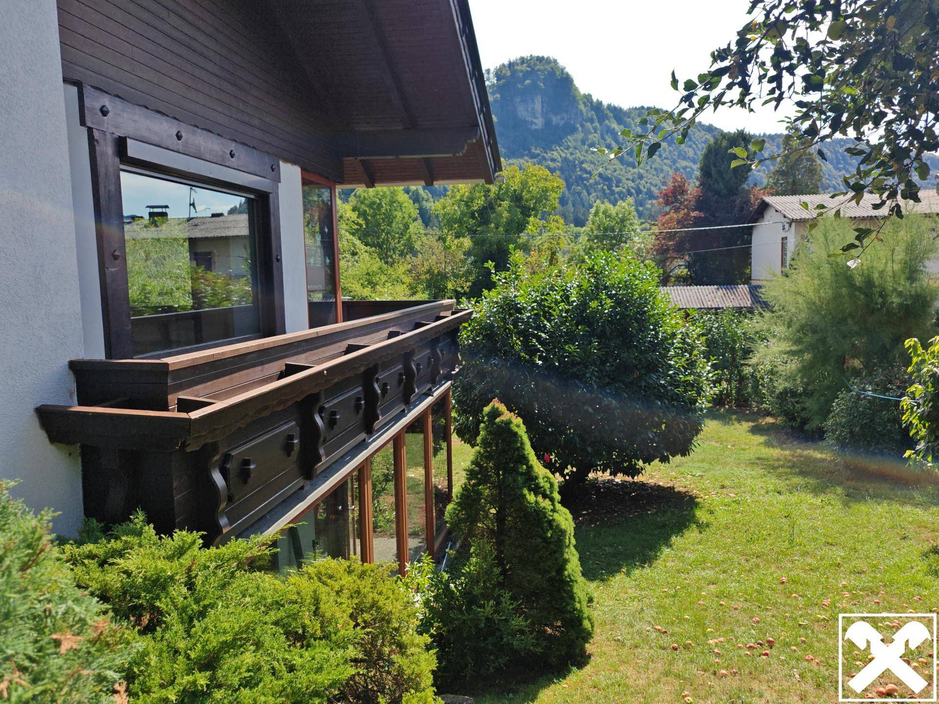Kleiner Holzbalkon mit traditionellen Schnitzereien und Blick auf den grünen Gartenbereich.