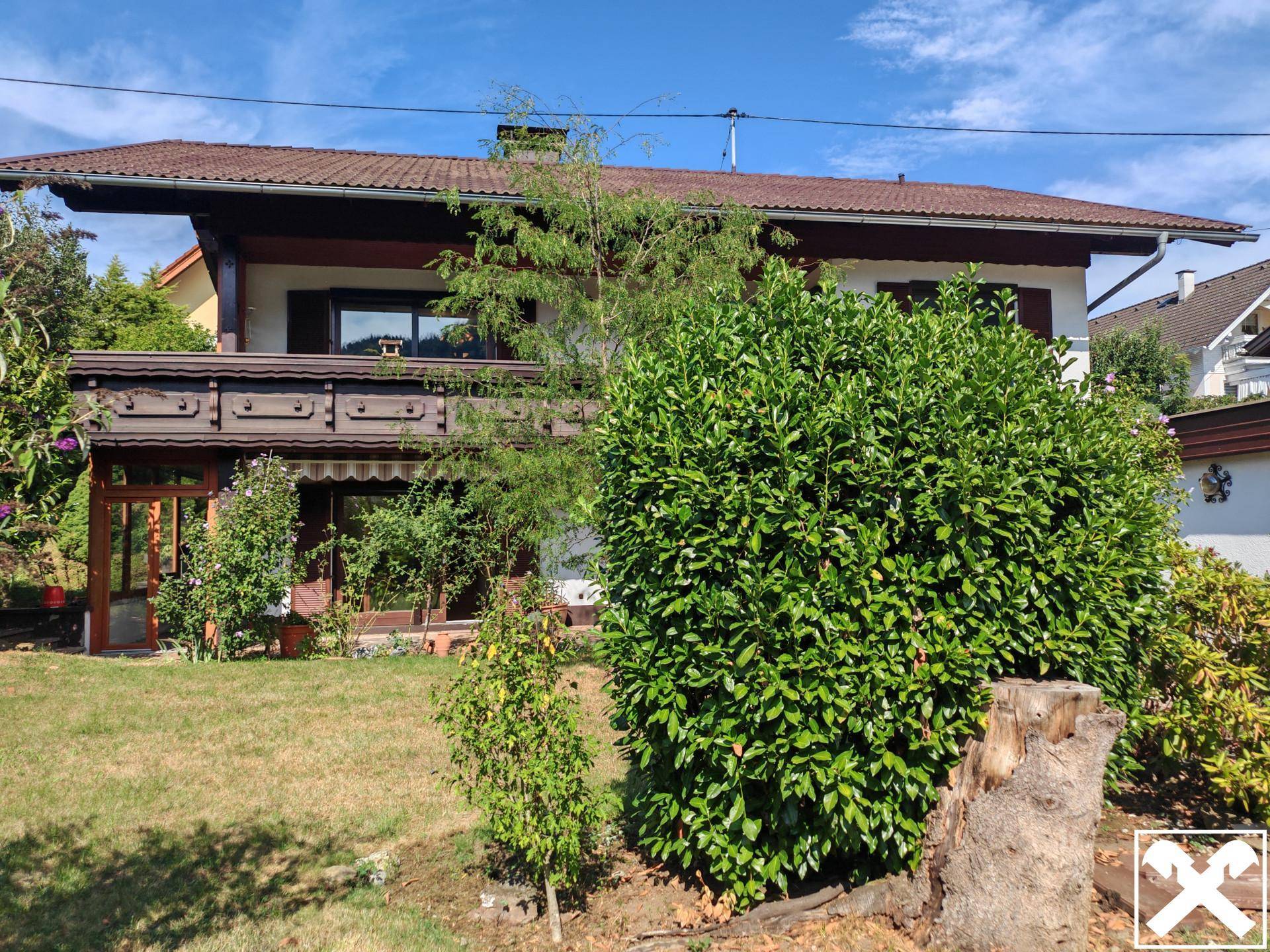 Vorderansicht des Hauses mit großem Busch im Garten und traditioneller Architektur.