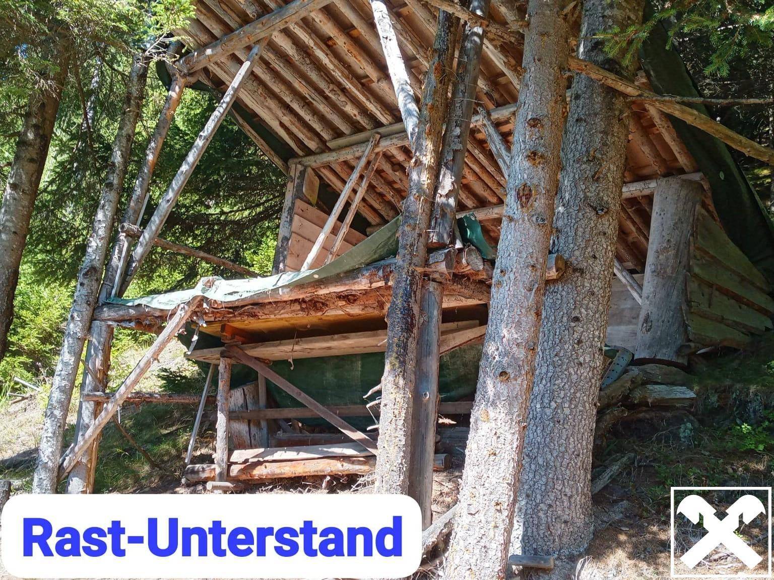 Ein einfacher, rustikaler Unterstand aus Holz befindet sich mitten im Wald.