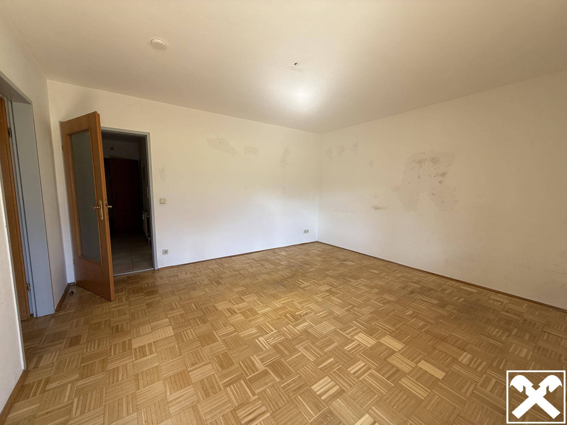 Geräumiges Zimmer mit Parkettboden und Holztür, bereit für individuelle Gestaltung.