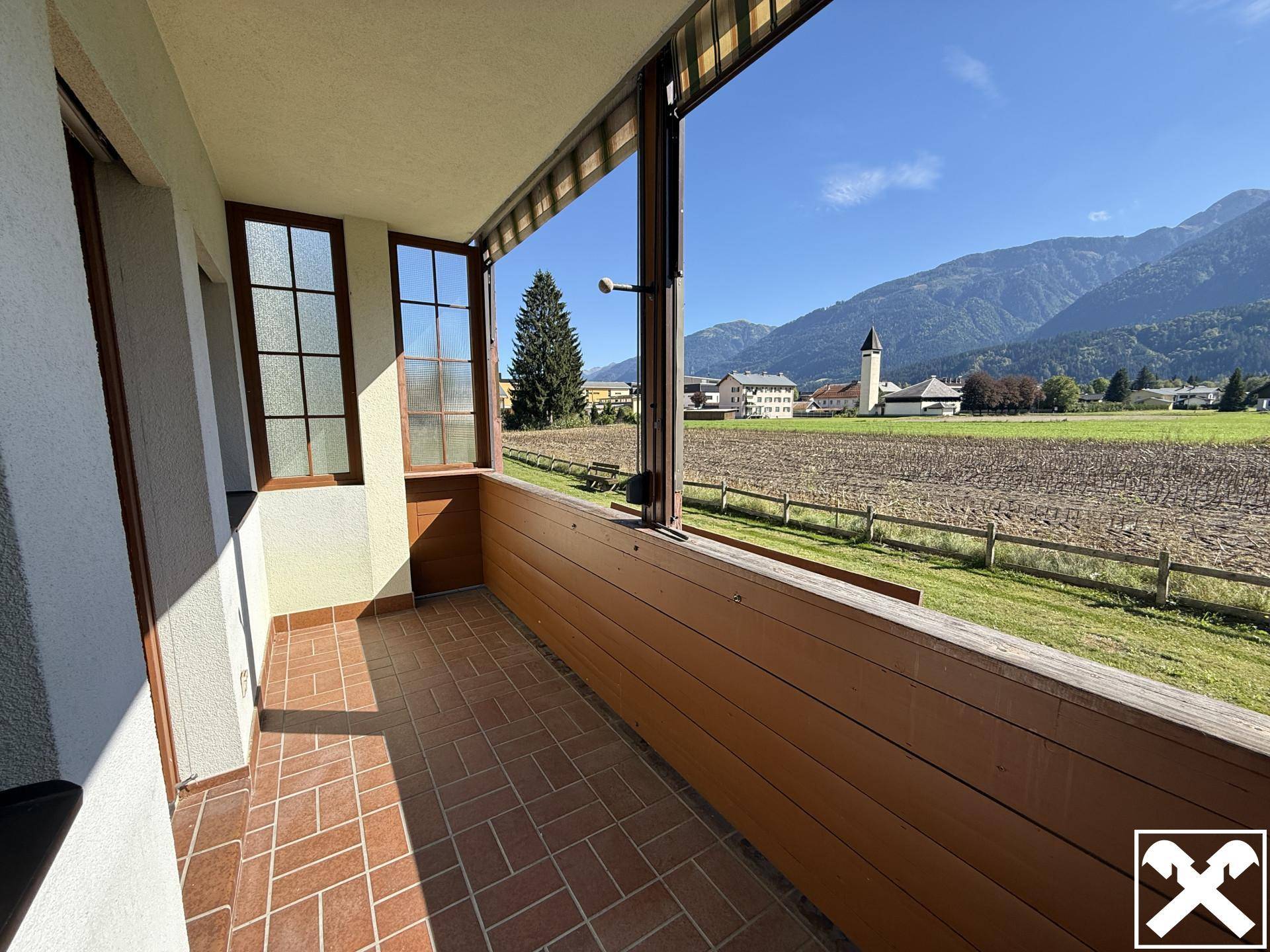 Überdachter Balkon mit Fliesenboden und weitem Blick auf die umliegende Landschaft und Berge.