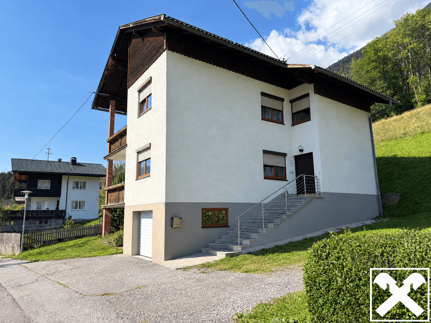 Seitenansicht des Hauses mit integrierter Garage, Außentreppe und Balkon im Obergeschoss.