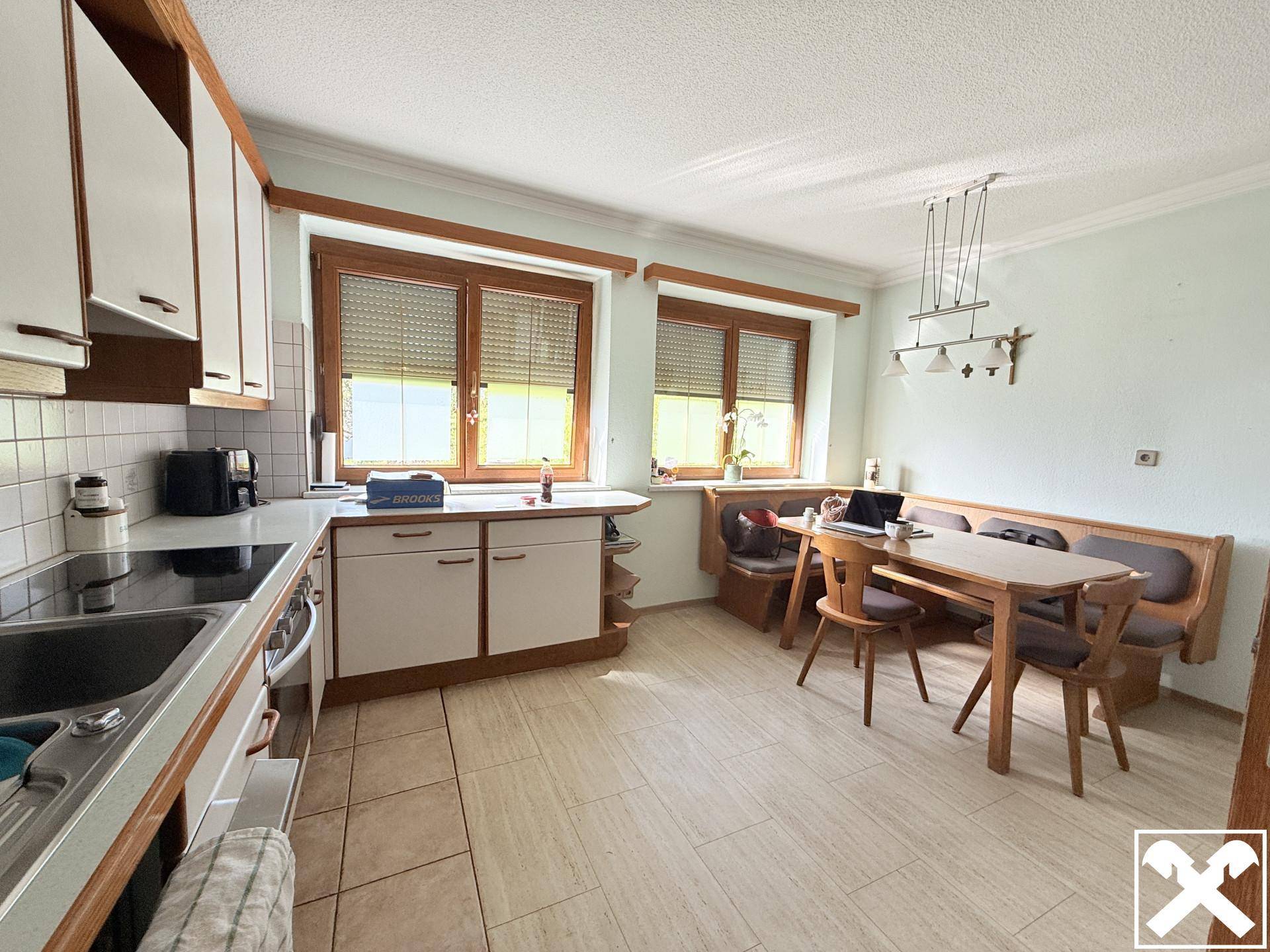 Gemütliche Wohnküche mit Essbereich, Holzmöbeln und Blick ins Grüne.