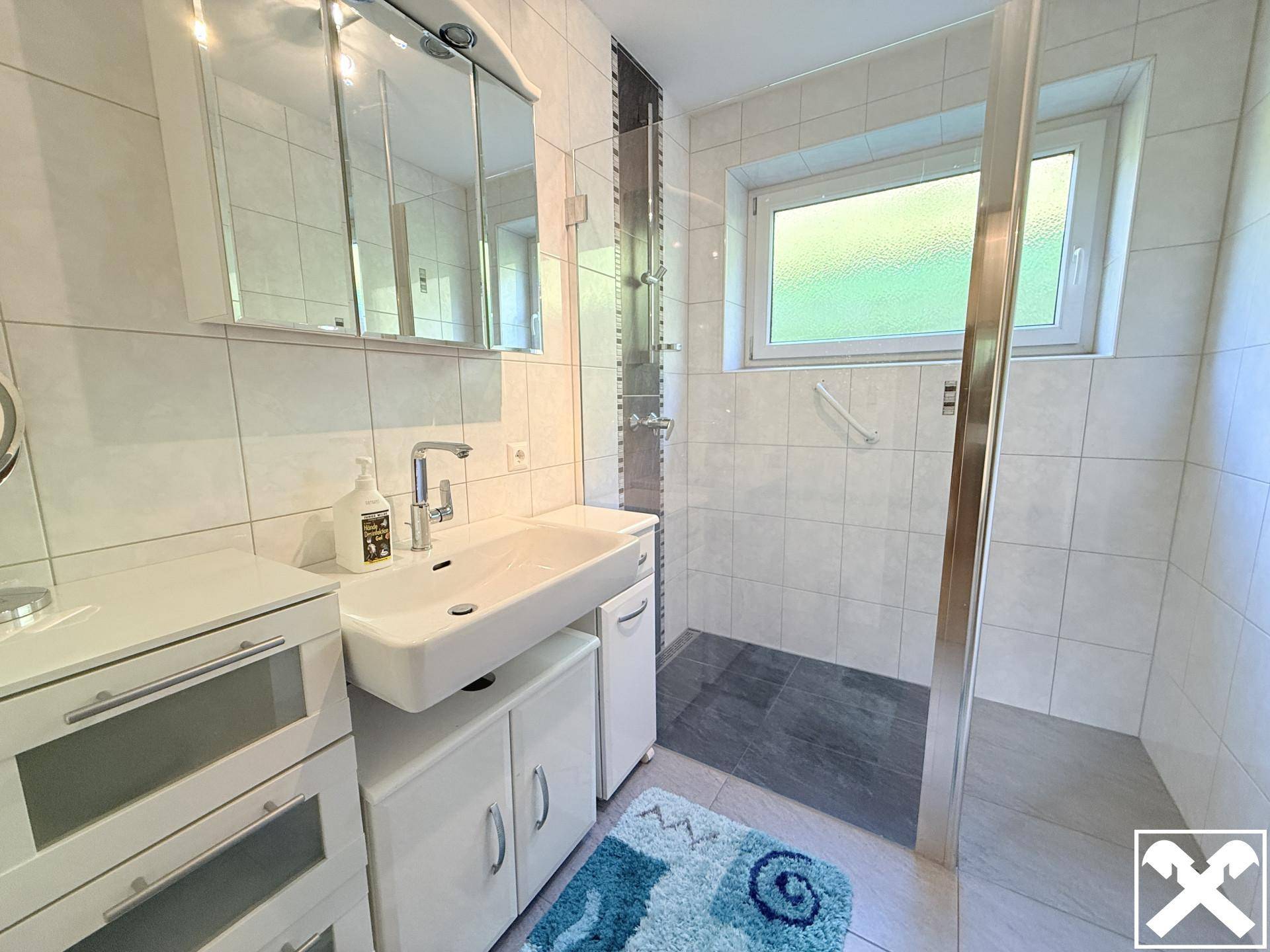 Modernes Badezimmer mit ebenerdiger Dusche, Fenster und weißen Fliesen.