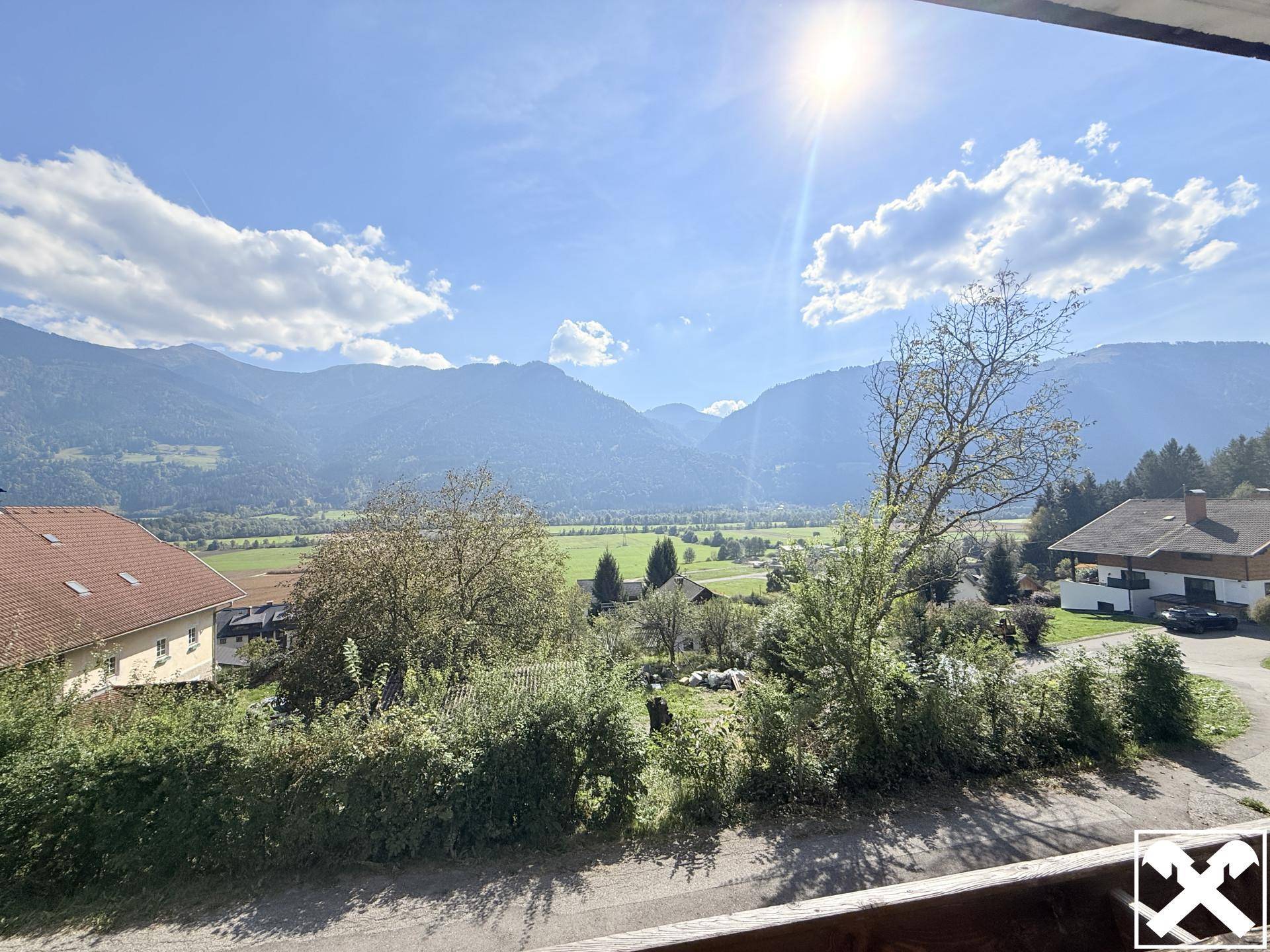Geräumiger Balkon mit Panoramablick auf die Berge und das Tal an einem sonnigen Tag.