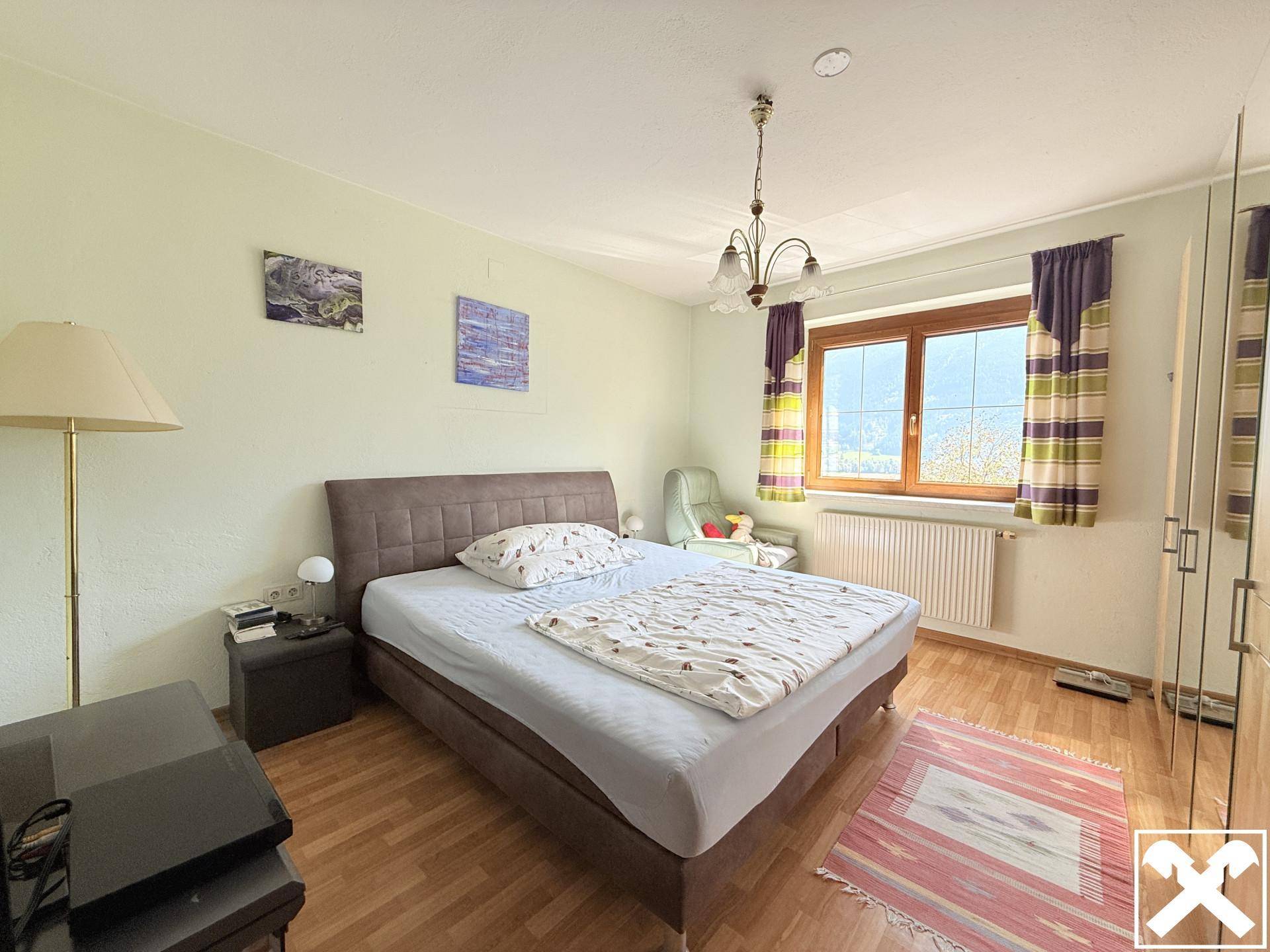 Gemütliches Schlafzimmer mit Doppelbett, Holzfußboden und Fenster mit Bergblick.