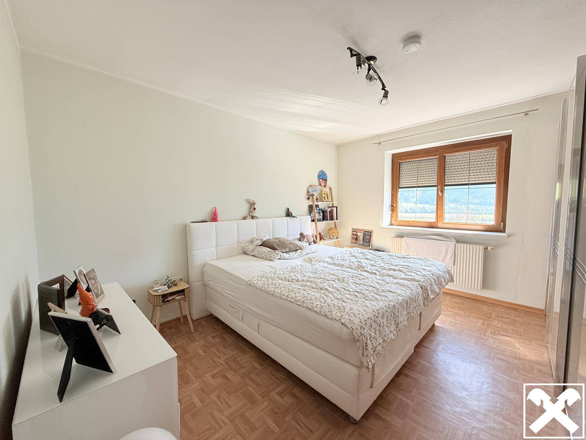 Geräumiges Schlafzimmer mit Doppelbett, Parkettboden und Fenster mit Bergblick.