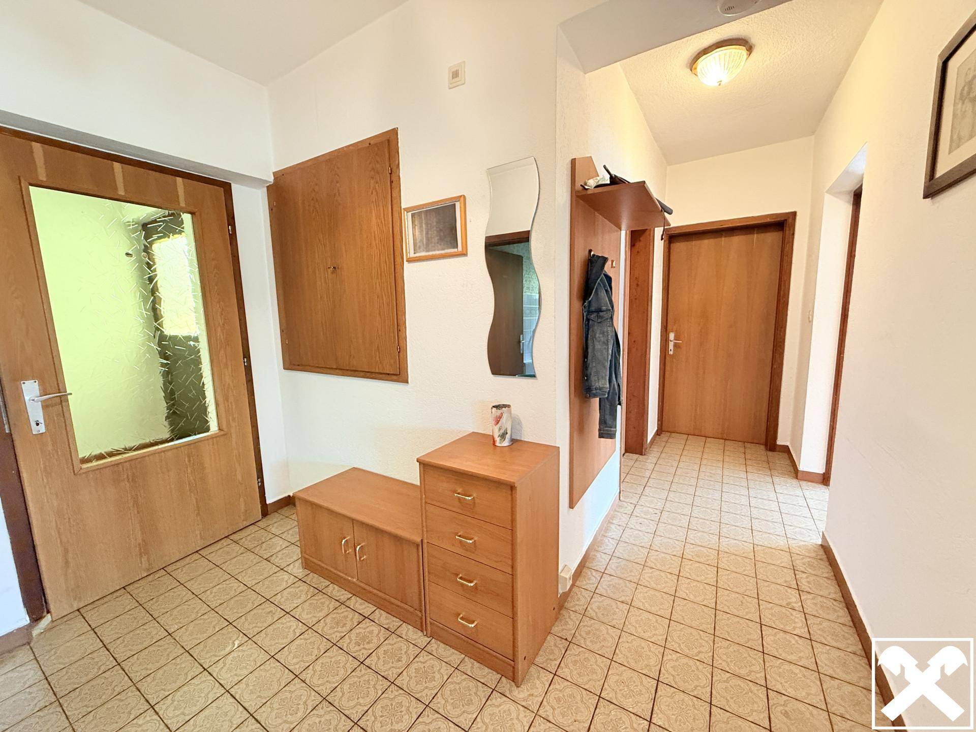 Heller Eingangsbereich mit Fliesenboden, Garderobe und Holzmöbeln.