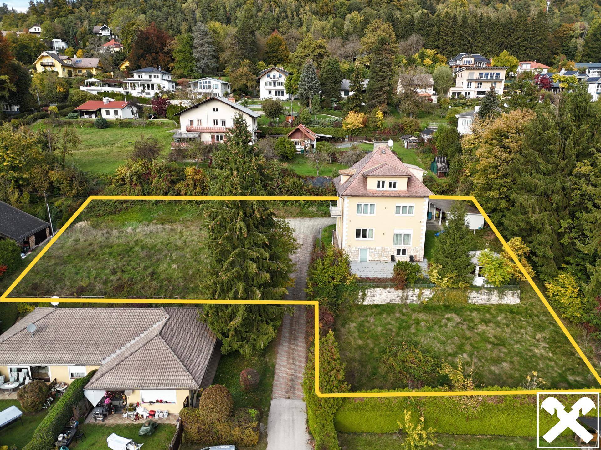 Weitläufiges Grundstück mit einem Haus und viel Grün, umgeben von bewaldeten Hügeln.