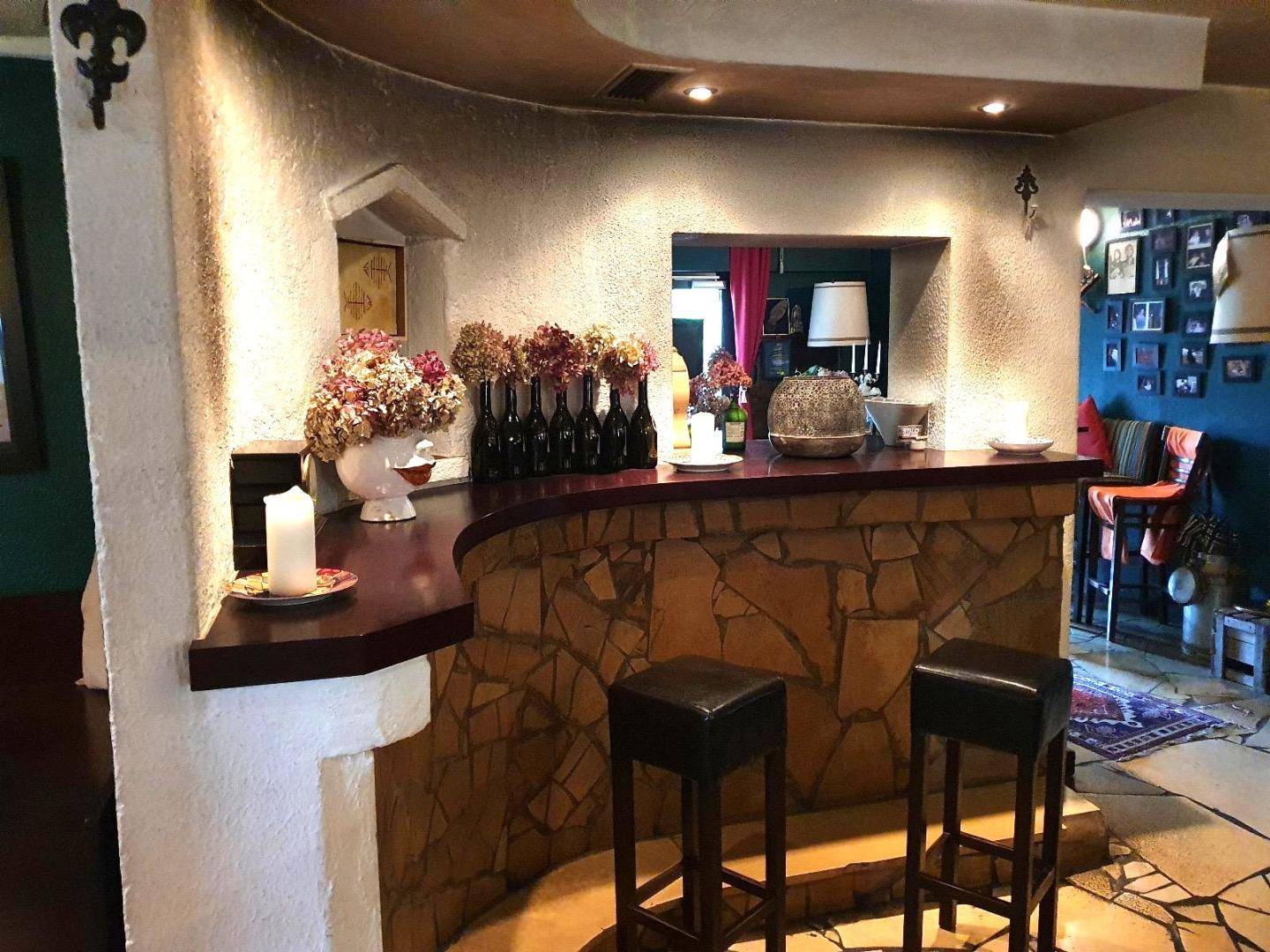 Gemütliche Bar mit einer Theke aus Naturstein und dunkler Holzplatte, ergänzt durch Barhocker und dekorative Elemente.