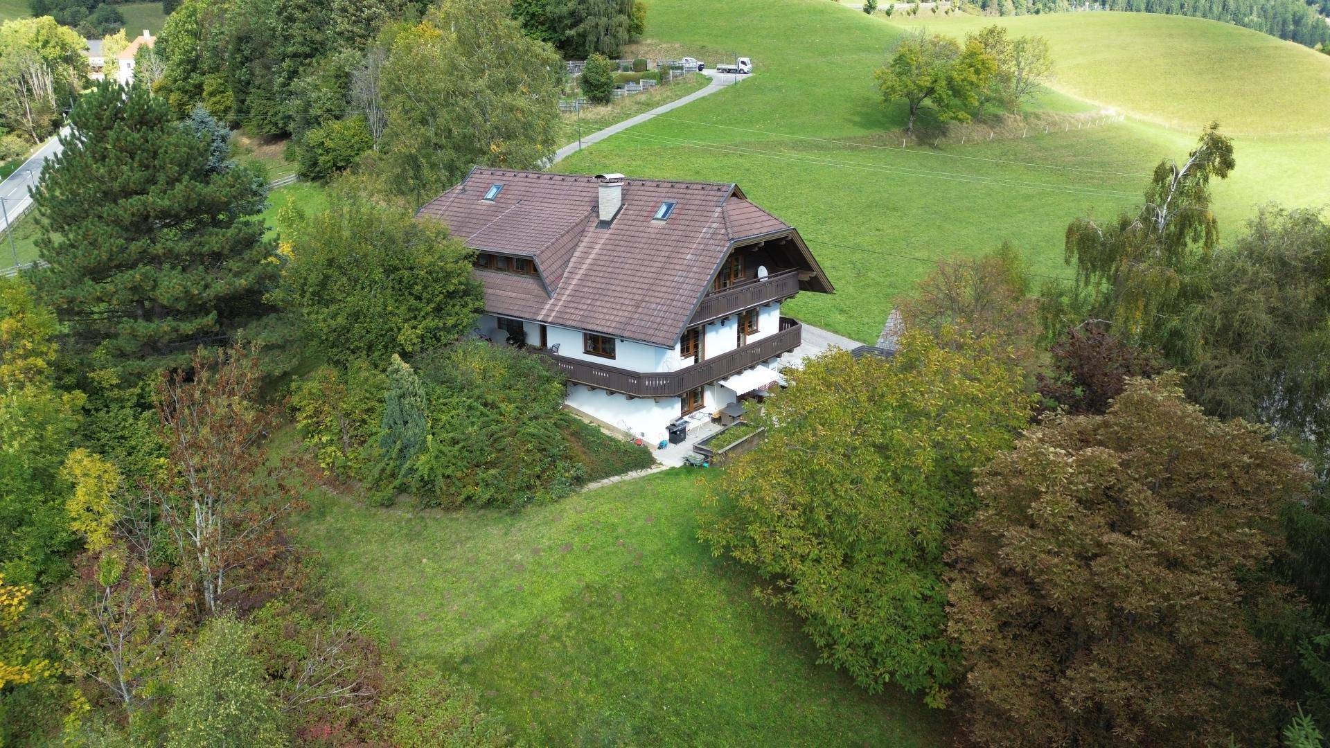 Freistehendes Haus in idyllischer Hügellandschaft, umgeben von Bäumen und Wiesen.