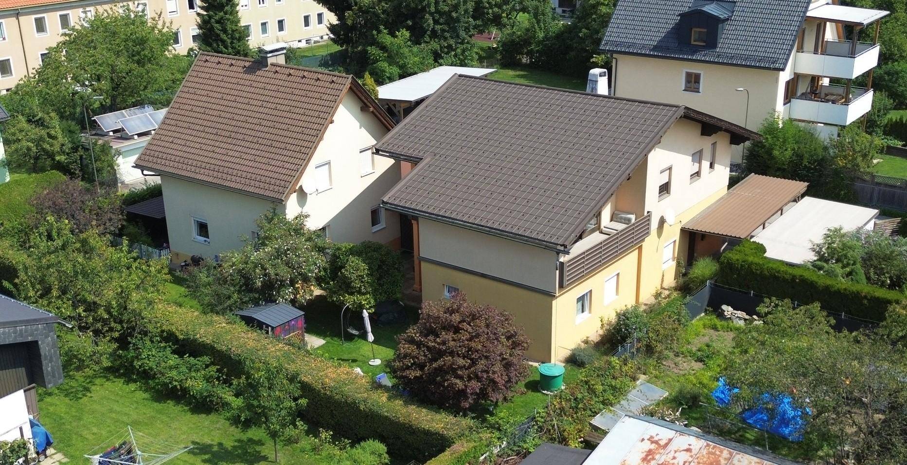 Luftaufnahme eines Wohnhauses mit braunem Ziegeldach und gepflegtem Gartenbereich in einer Wohnsiedlung.
