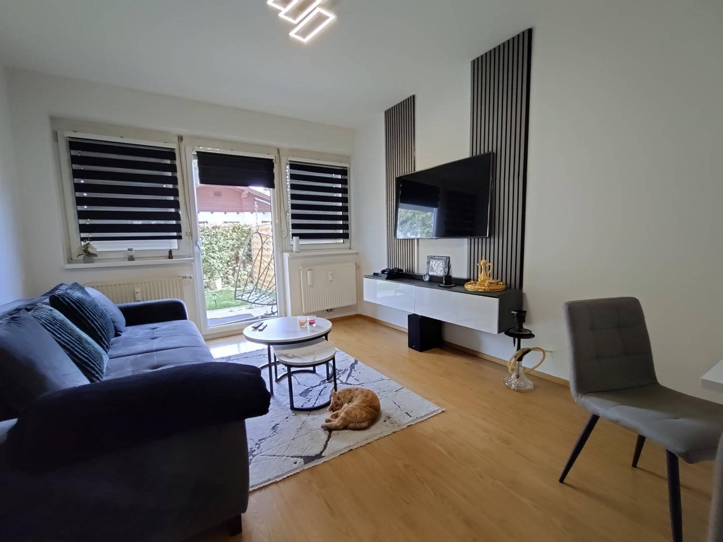 Gemütliches Wohnzimmer mit Sofa, Fernseher und direktem Zugang zum Gartenbereich.