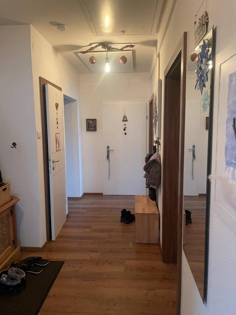 Eingangsbereich mit Holzfußboden, Spiegel und Garderobe für Besucher.