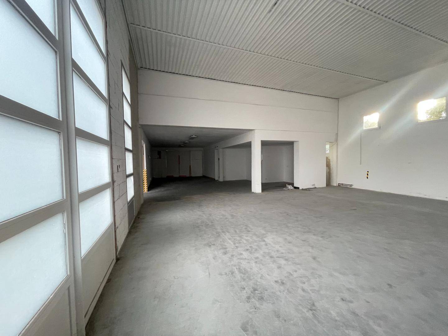 Weitläufige, leere Lagerhalle mit hohen Decken, großen Rolltoren und Betonboden, bereit für verschiedene Nutzungen.