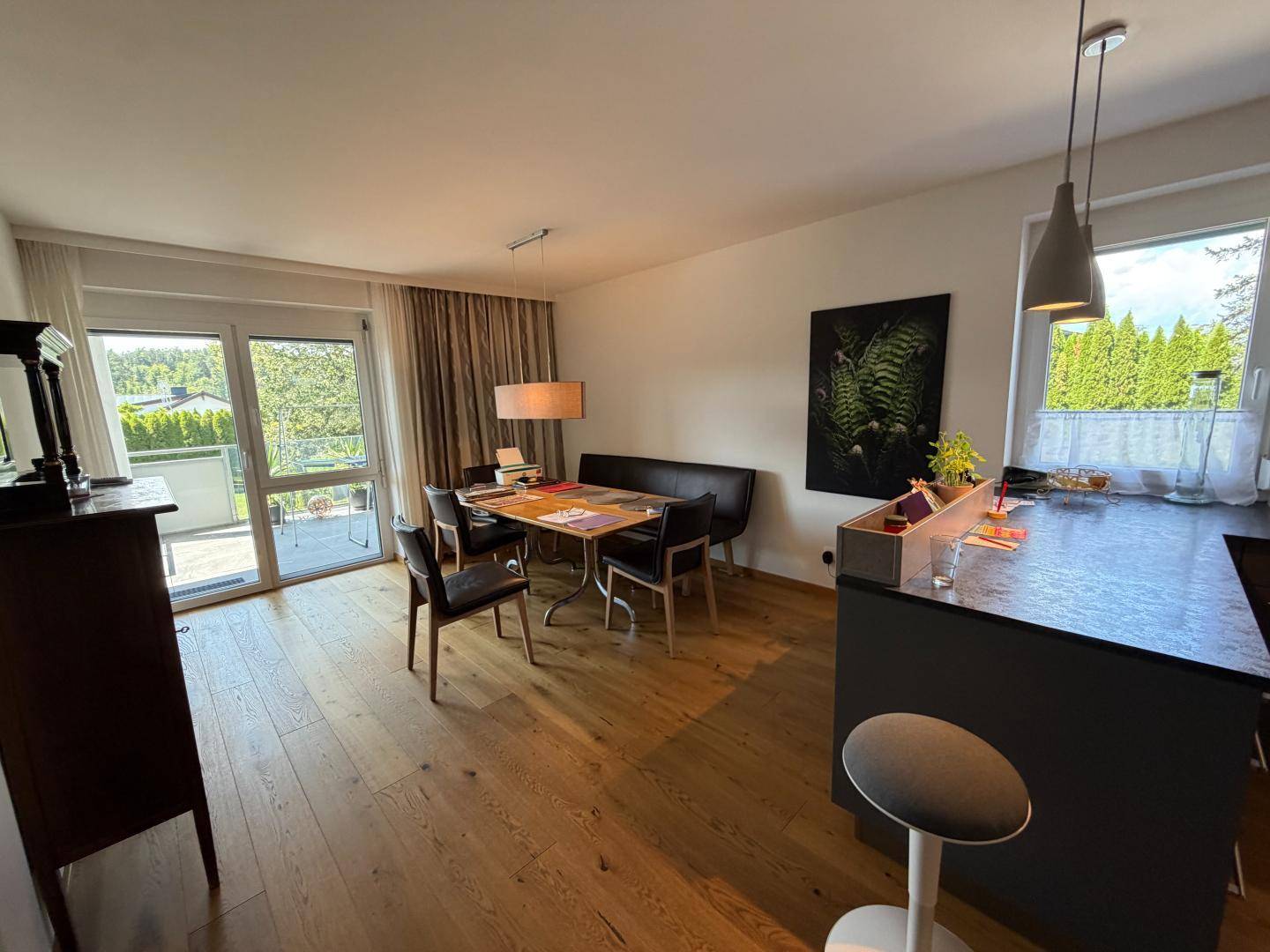 Heller Wohn-Essbereich mit Holzboden, Esstisch und Zugang zu einem Balkon.