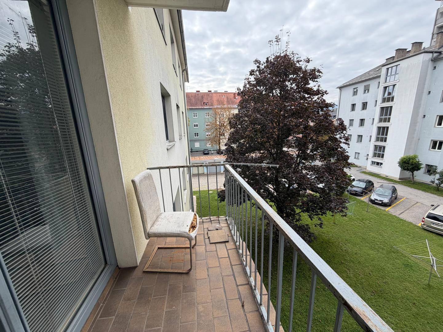 Kleiner Balkon mit Fliesenboden und Blick auf den Innenhof und umliegende Gebäude.