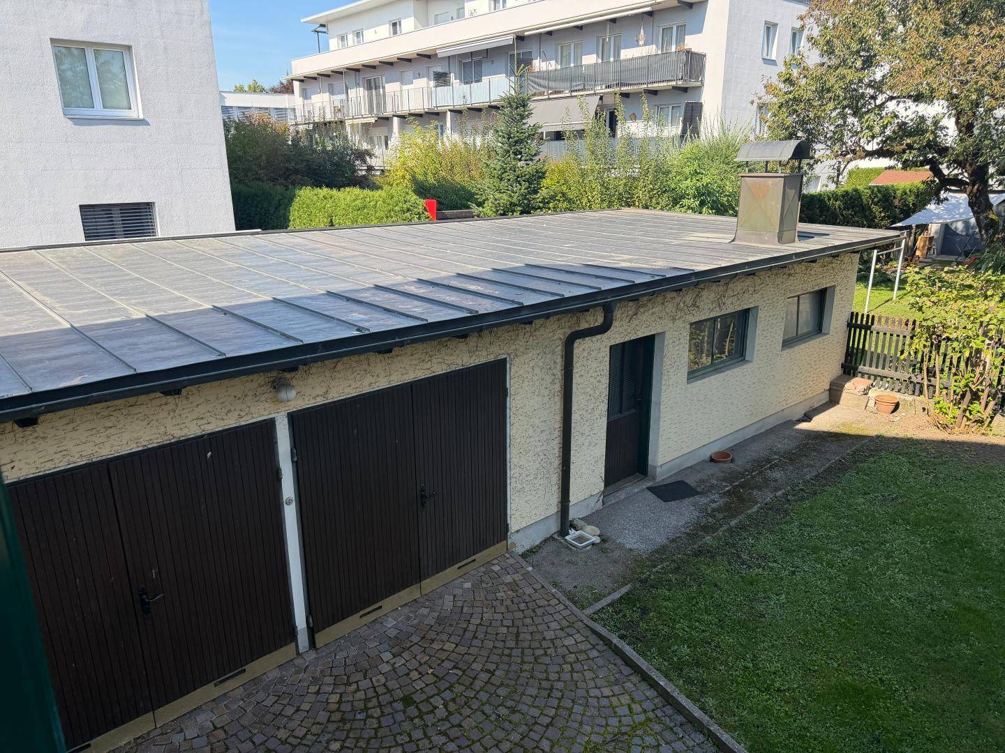 Freistehende Garage mit zwei Toren und Flachdach, umgeben von einem gepflegten Rasenbereich.