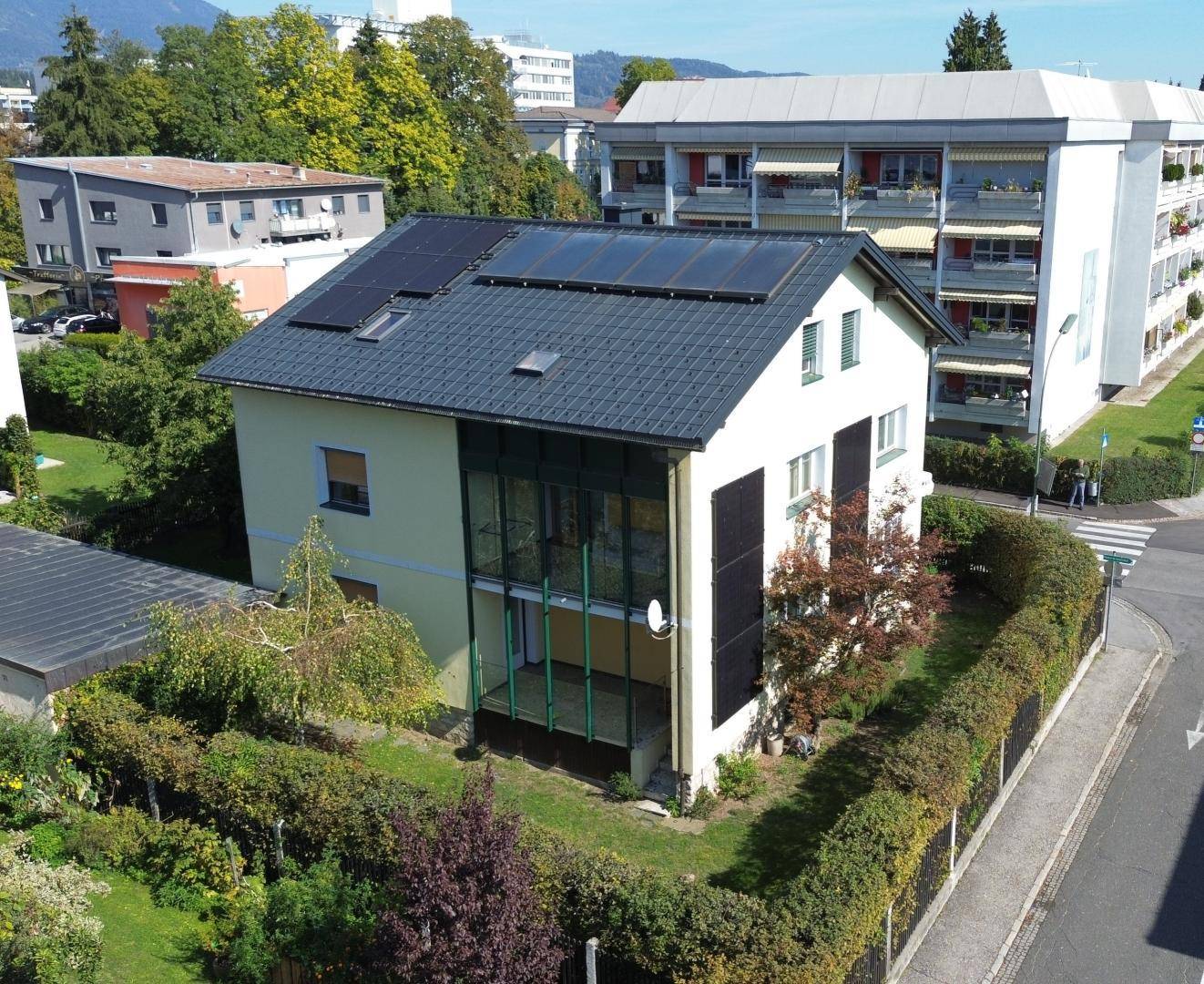 Ansicht des Hauses von der Rückseite mit Photovoltaikanlage auf dem Dach und verglastem Anbau.