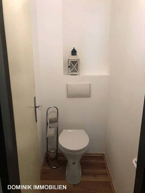 Separates Gäste-WC mit wandhängender Toilette und Laminatboden, schlicht und funktional.