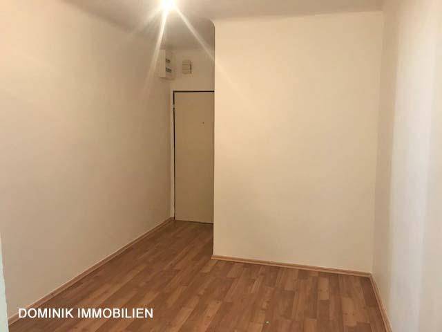 Leeres Zimmer mit Laminatboden und weiß gestrichenen Wänden, bereit zur individuellen Gestaltung.