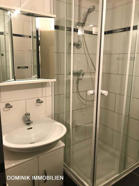 Modernes Badezimmer mit Duschkabine, Waschbecken, Spiegelschrank und weißen Fliesen.