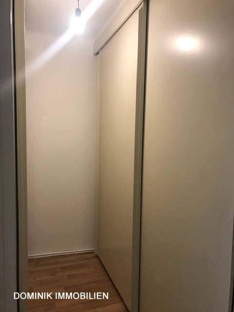 Kleiner Abstellraum oder begehbarer Schrank mit Schiebetüren und Laminatboden.