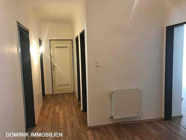 Langer Flur mit Laminatboden, der zu einer Eingangstür oder einem weiteren Zimmer führt.
