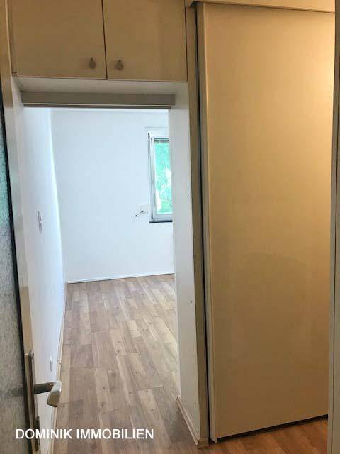 Blick aus einem Abstellbereich in einen Flur mit Laminatboden und Zugang zu weiteren Räumen.