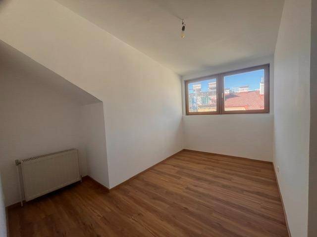 Schlafzimmer mit Holzboden, großem Fenster und Dachschräge.