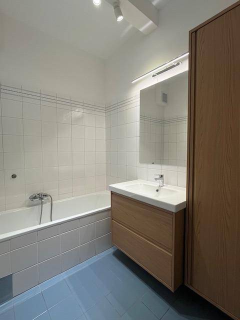 Badezimmer mit Badewanne, modernem Waschtisch und blauen Bodenfliesen.