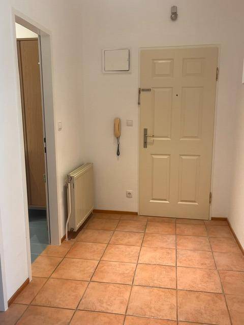 Heller Flur mit Terrakottafliesen und Zugang zur Wohnungstür.