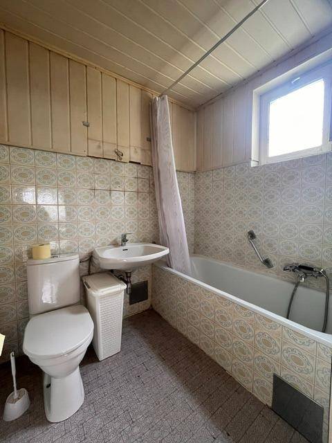 Badezimmer mit Badewanne, WC, Waschbecken und einem Fenster für Tageslicht.