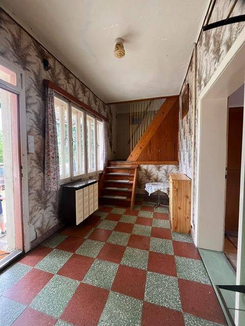Heller Eingangsbereich mit kariertem Fliesenboden, Holztreppe und Fenster zum Garten.