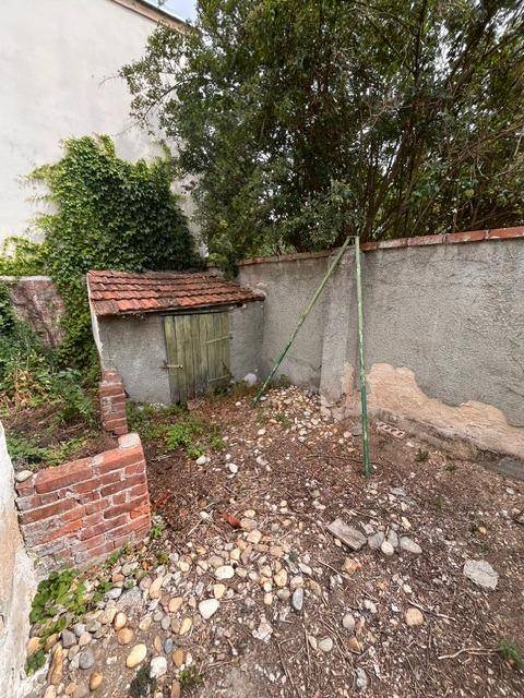 Kleiner, verwilderter Gartenbereich mit einem gemauerten Schuppen und alten Mauern.