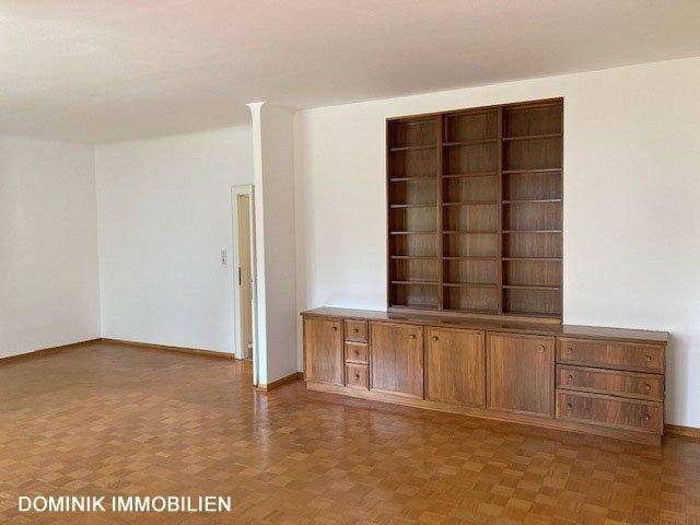 Wohnzimmer mit Parkettboden und einer großen, eingebauten Holzschrankwand.