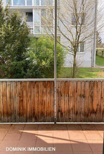 Balkon mit Fliesenboden und Holzgeländer, bietet einen Ausblick auf die grüne Umgebung.