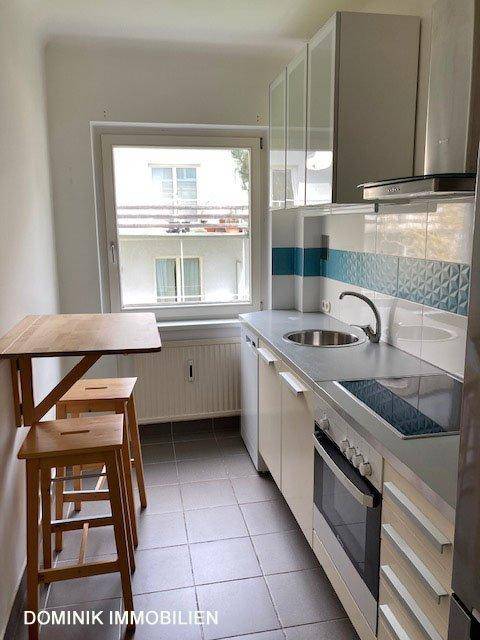 Kleine Küche mit Einbaugeräten, Klapptisch und Fenster mit Blick nach draußen.