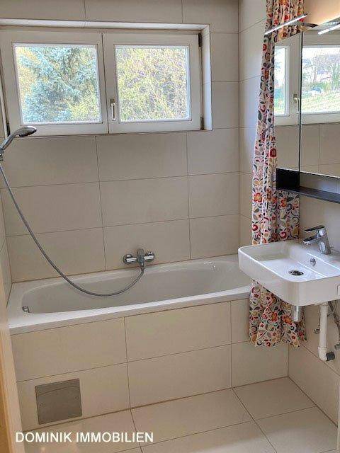 Badezimmer mit Badewanne, Duschvorrichtung, Waschbecken und Fenster für Tageslicht.