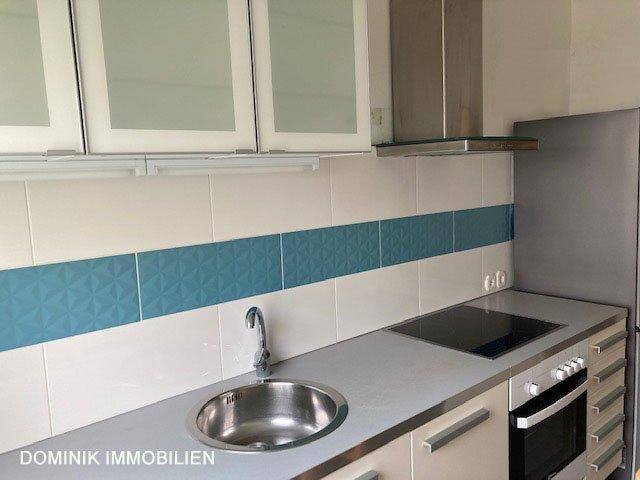 Moderne Küchenzeile mit blauen Akzentfliesen, Spüle und Induktionskochfeld.