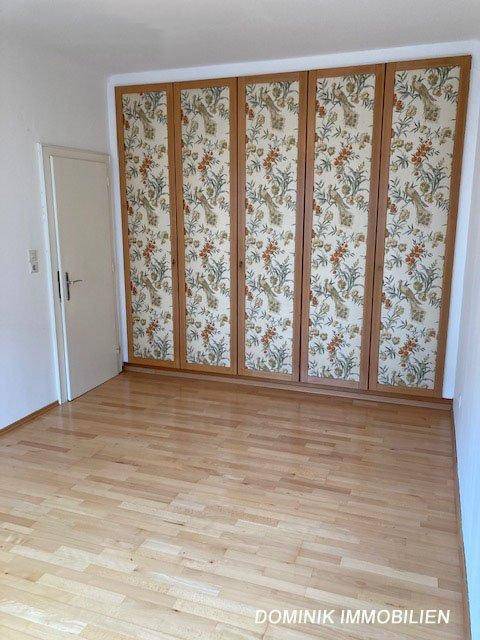 Schlafzimmer mit Parkettboden und einer großen, gemusterten Einbauschrankwand.