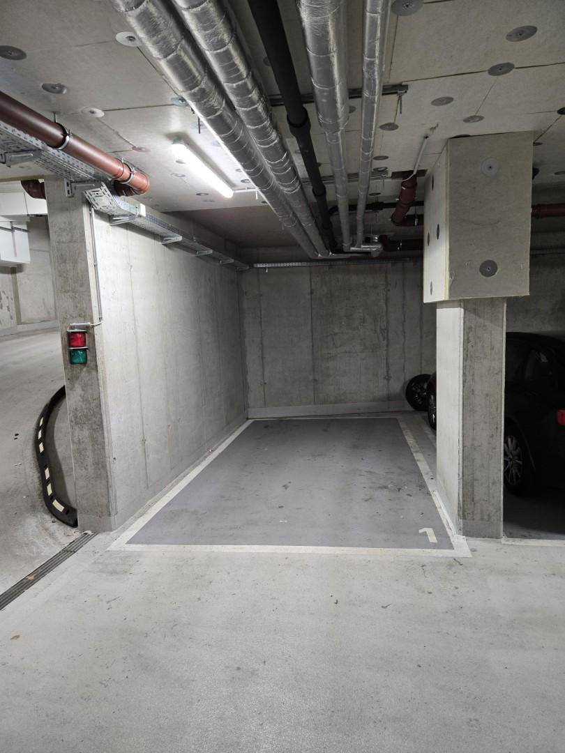 Einzelner Stellplatz Nummer 1 in einer Tiefgarage mit Betonpfeilern und Deckeninstallationen.