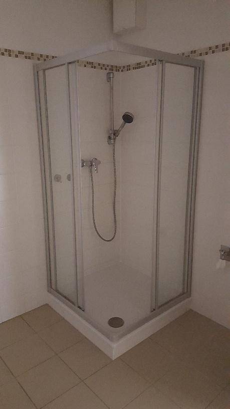Eckduschkabine mit Glaswänden und weißen Fliesen in einem Badezimmer.