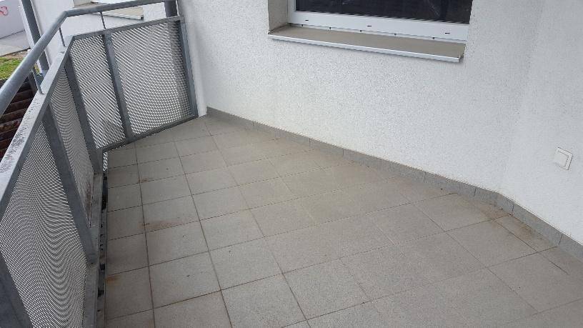 Eckbereich eines Balkons mit grauen Fliesen und robustem Metallgeländer.