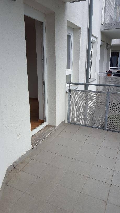 Balkon mit Fliesenboden und Metallgeländer, direkt zugänglich vom Innenbereich der Wohnung.