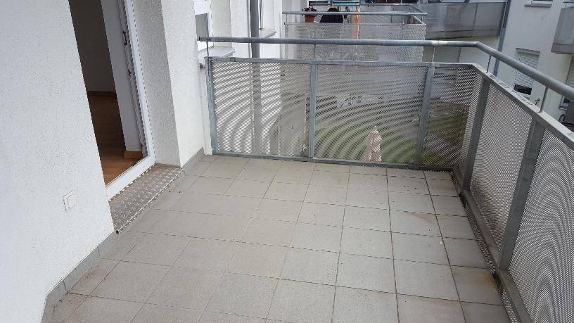 Geräumiger Balkon mit grauen Fliesen und Metallgeländer, ideal für Entspannung im Freien.