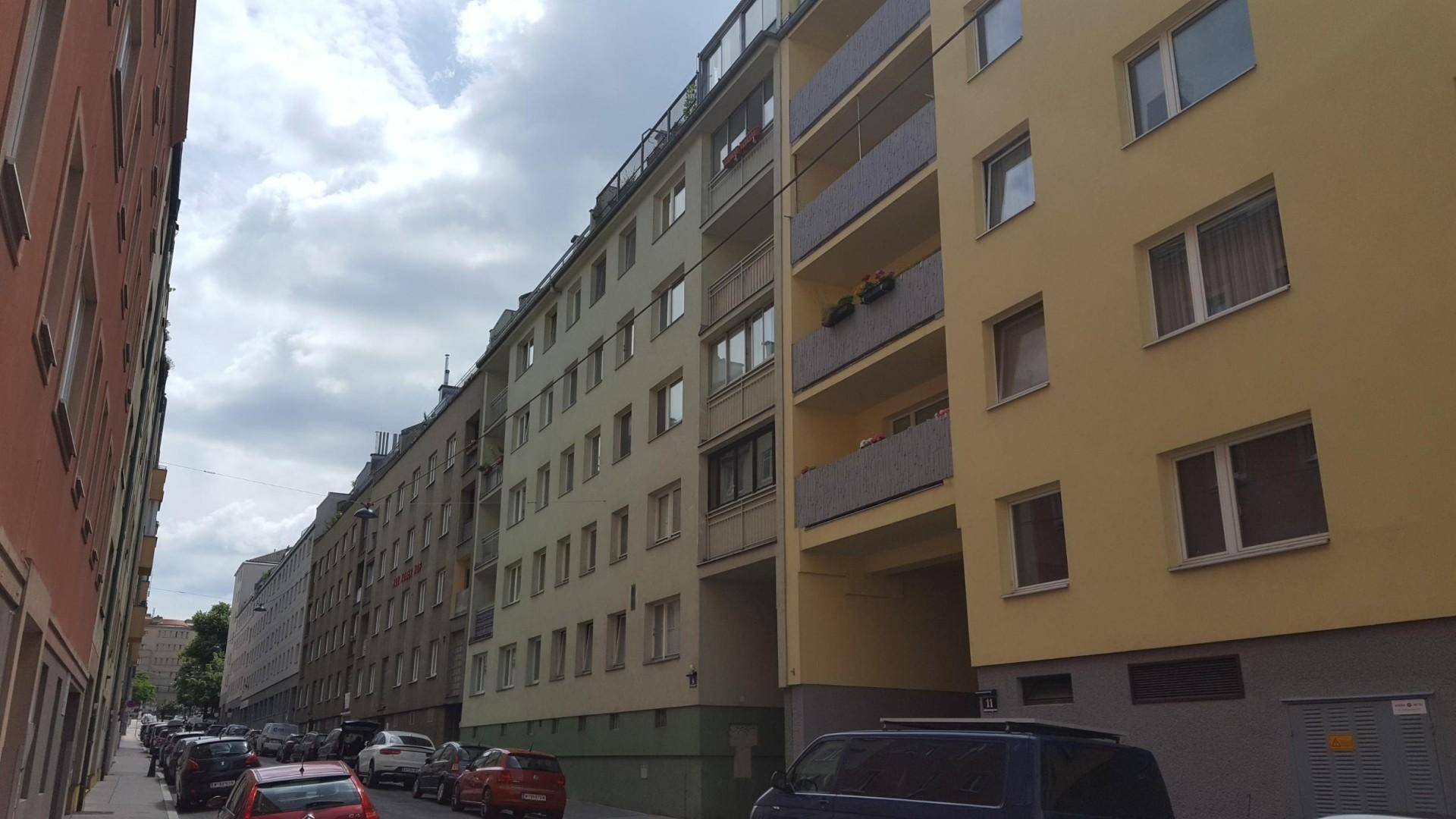 Straßenansicht eines Wohnviertels mit mehreren Gebäuden und parkenden Autos.