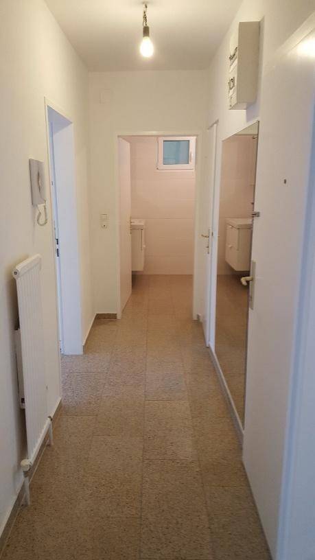 Langer Flur mit Fliesenboden, der zu einem Badezimmer und weiteren Räumen führt.
