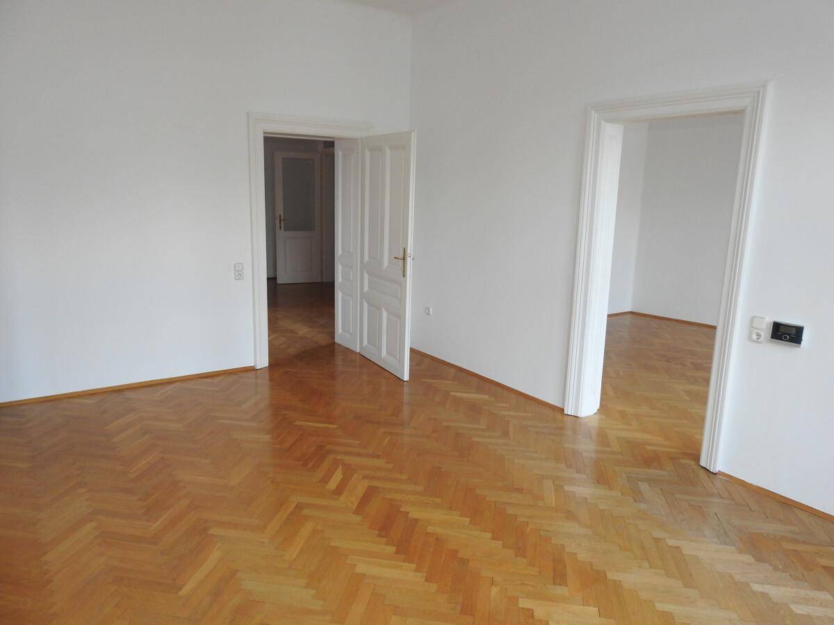 Großes Zimmer mit mehreren Türen, die zu verschiedenen Bereichen der Wohnung führen.
