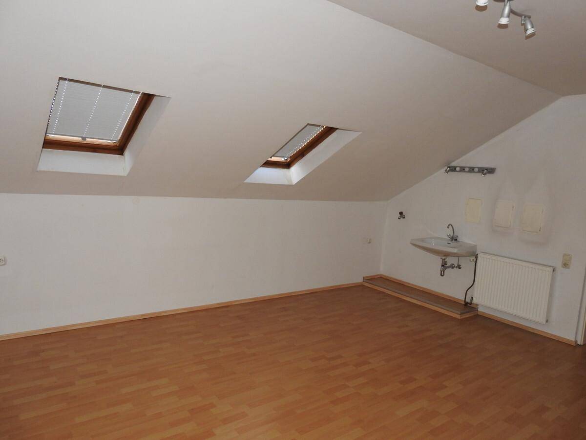 Ausgebauter Dachboden mit Holzboden, zwei Dachfenstern und einem integrierten Waschbecken.